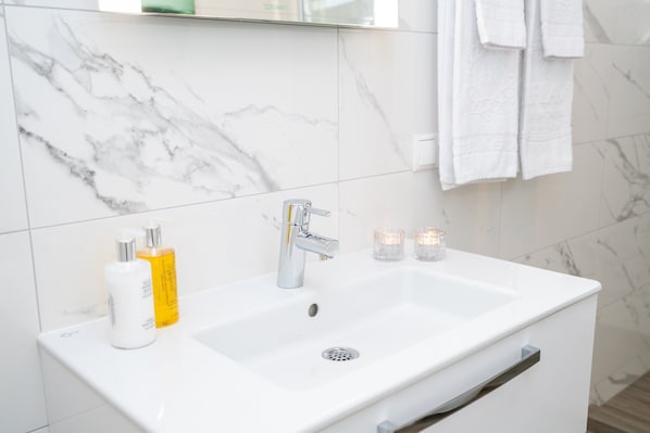 A bathroom with a white sink, marble tiles, and a towel rack.