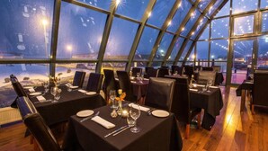 Un restaurante con mesas dispuestas para comer, ventanas amplias y vistas al exterior.