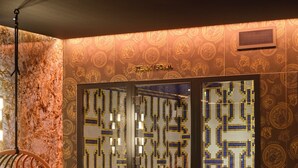 Una habitación con pared de mosaico, un sillón colgante con cojín estampado y vistas a un estadio a través de un ventanal.