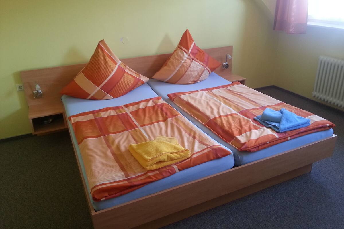 Una cama con una manta escocesa, dos almohadas y una toalla azul.
