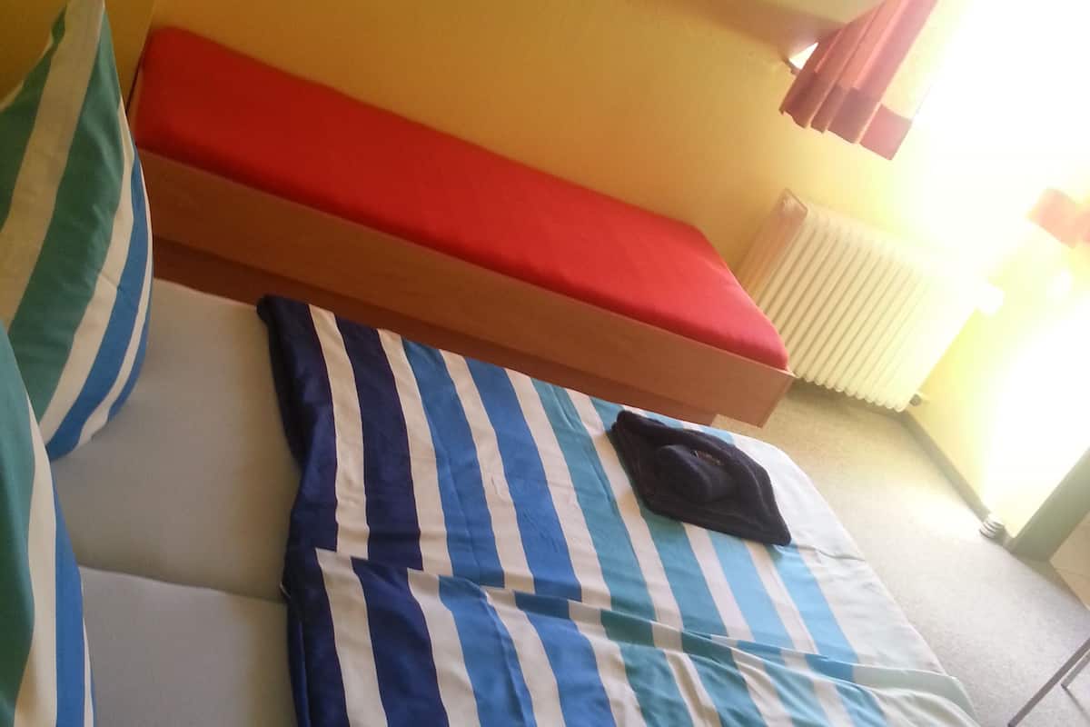 Una cama con ropa de cama a rayas, cabecera roja y almohadas con rayas.