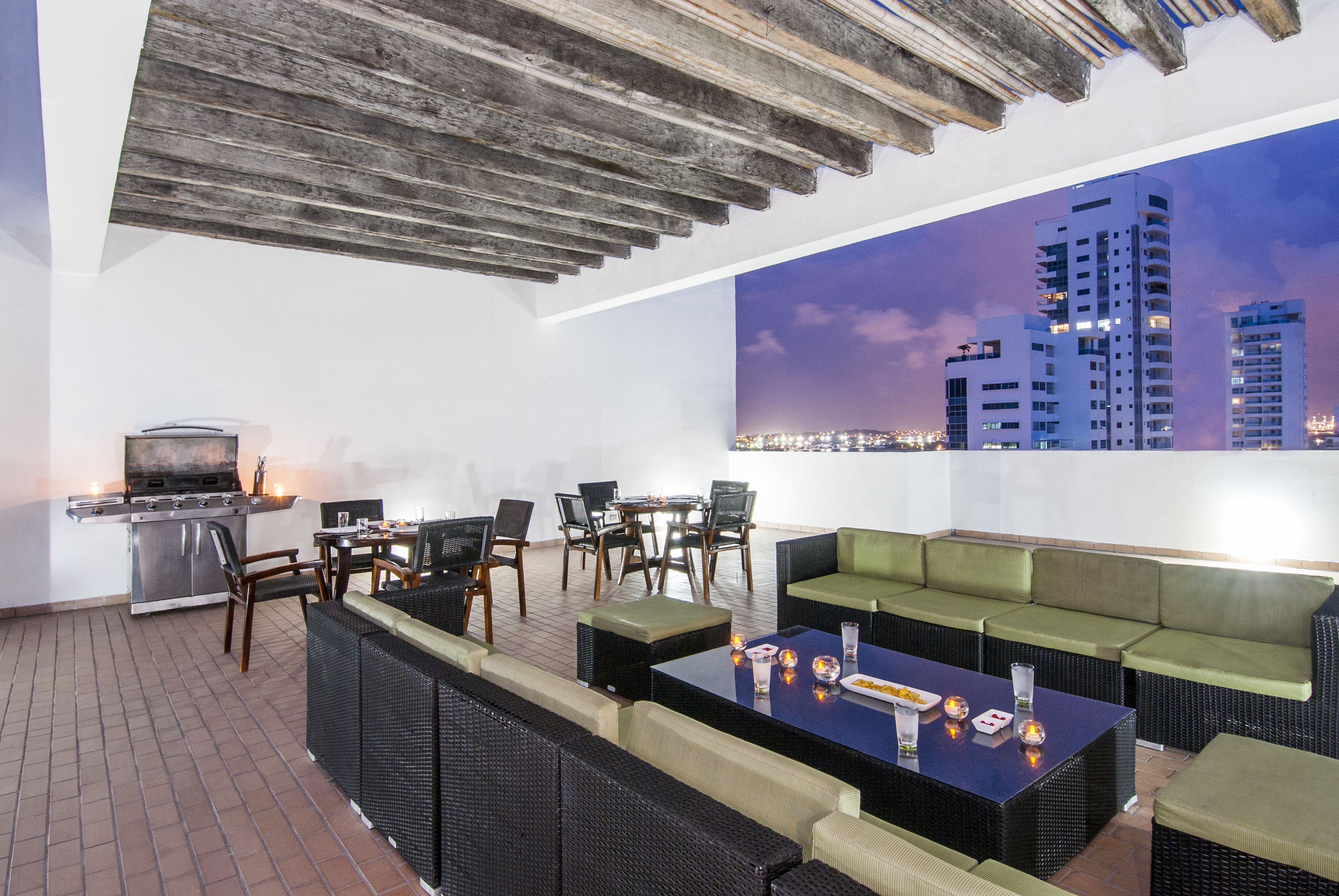 An outdoor patio with a grill, seating area, and a cityscape view.