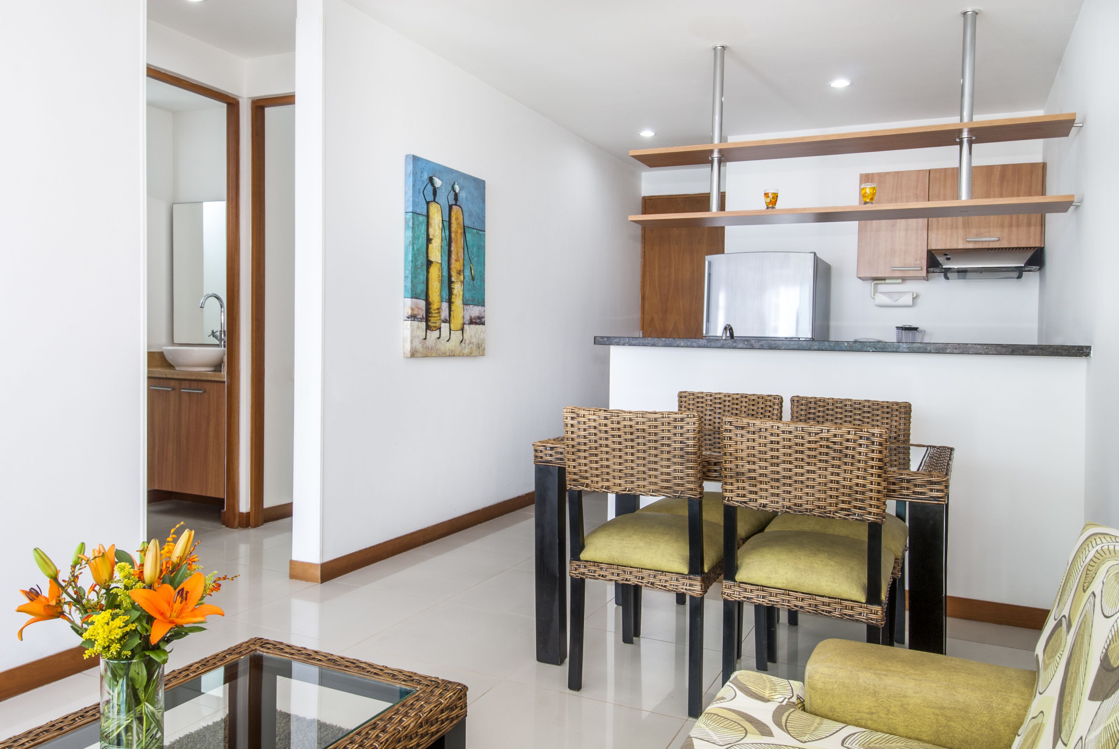 A modern living room with a dining area, a kitchen with wooden cabinets, and a painting on the wall.