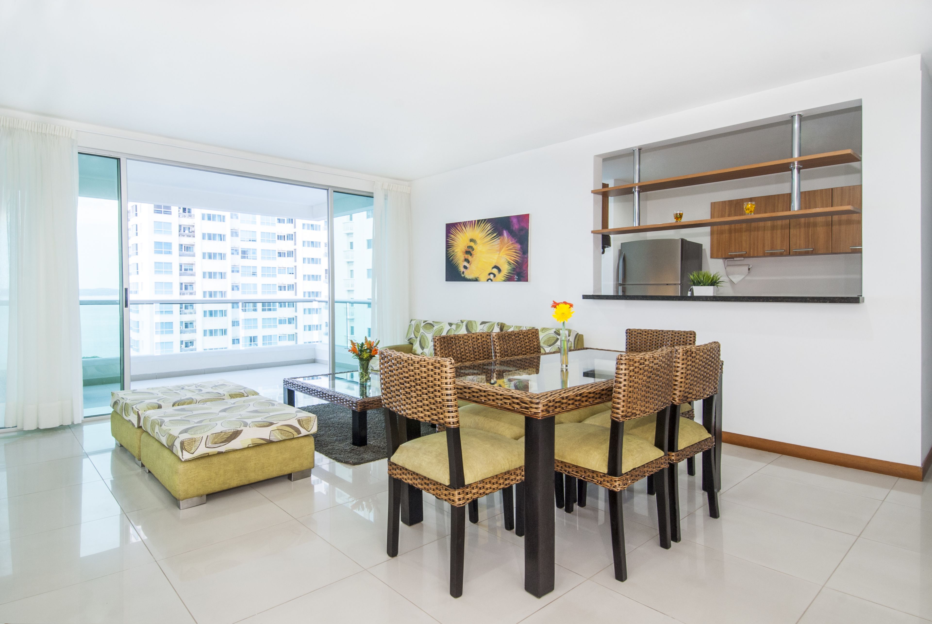 Una sala de estar moderna con comedor, ventanas amplias y vista a un edificio de gran altura.