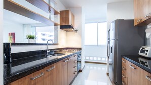 Una cocina moderna con armarios de madera, electrodomésticos de acero inoxidable y encimera negra.