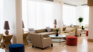 A modern living room with a beige sofa, armchairs, a coffee table, ottomans, and lamps. - Dammam Palace Hotel (Dammam)