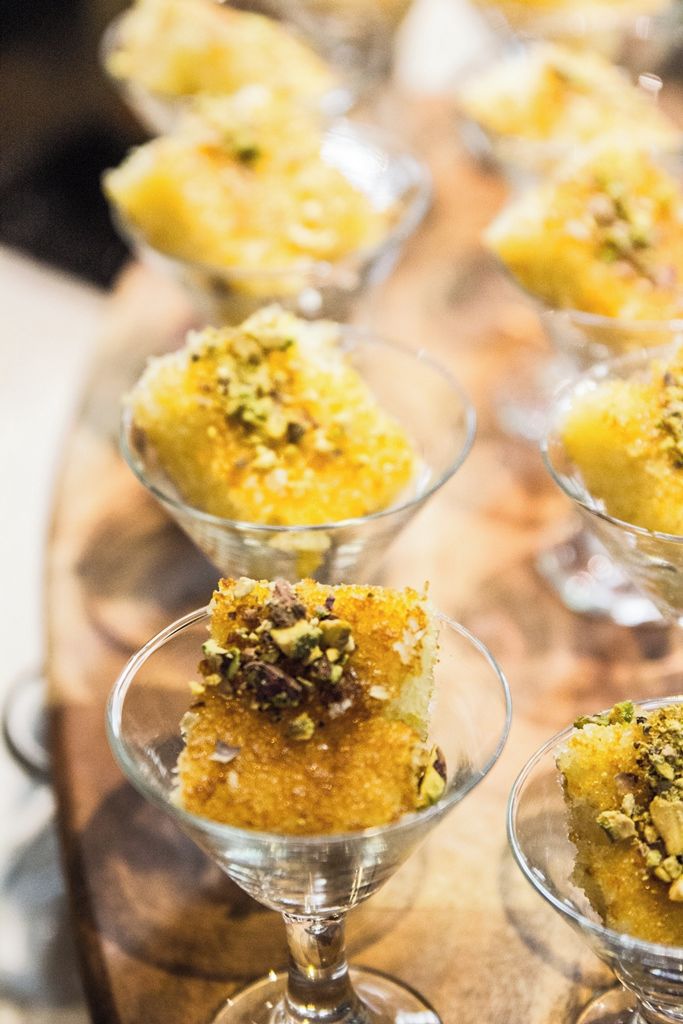 A dessert presentation in clear glass cups with a golden-brown base, garnished with chopped nuts.