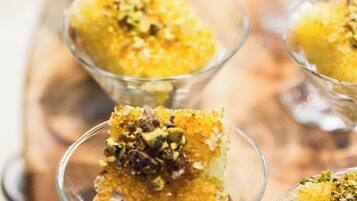 A dessert presentation in clear glass cups with a golden-brown base, garnished with chopped nuts.