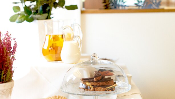 Une table de buffet avec divers plats, une carafe de jus de fruits et un verre de lait.