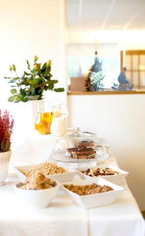 A buffet table with various food items, a pitcher of juice, and a glass of milk.