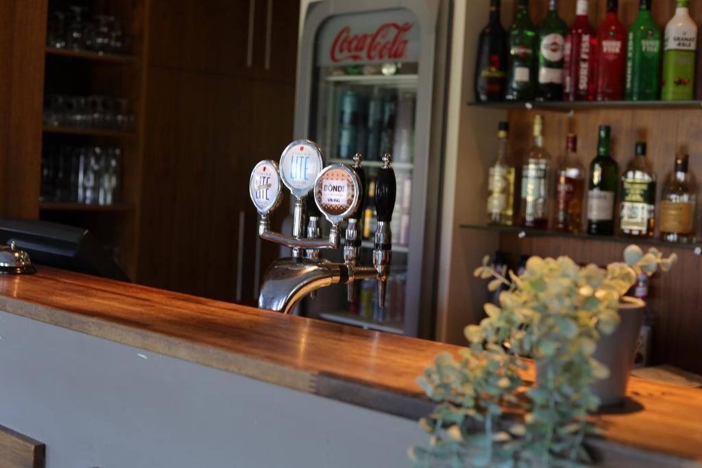 A bar area with a tap and shelves of liquor bottles.