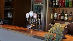 Un espace bar avec un robinet et des étagères remplies de bouteilles d’alcool.