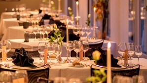 Een elegant gedekte tafel met meerdere tafels, kaarsen en glazen, wat wijst op een culinair hoogstandje.