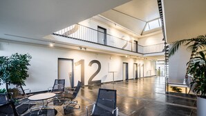 Een ruime lobby met een hoge plafond, een tussenverdieping en een modern design.