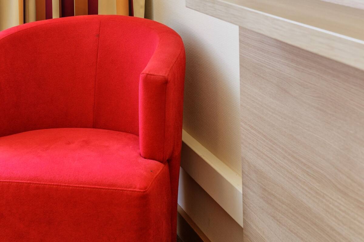 Ein roter Sessel neben einer Holztresen, über dem sich ein Fernseher befindet.