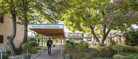 Un pasillo cubierto que conduce a un edificio con un cartel que dice "Herzlich willkommen".