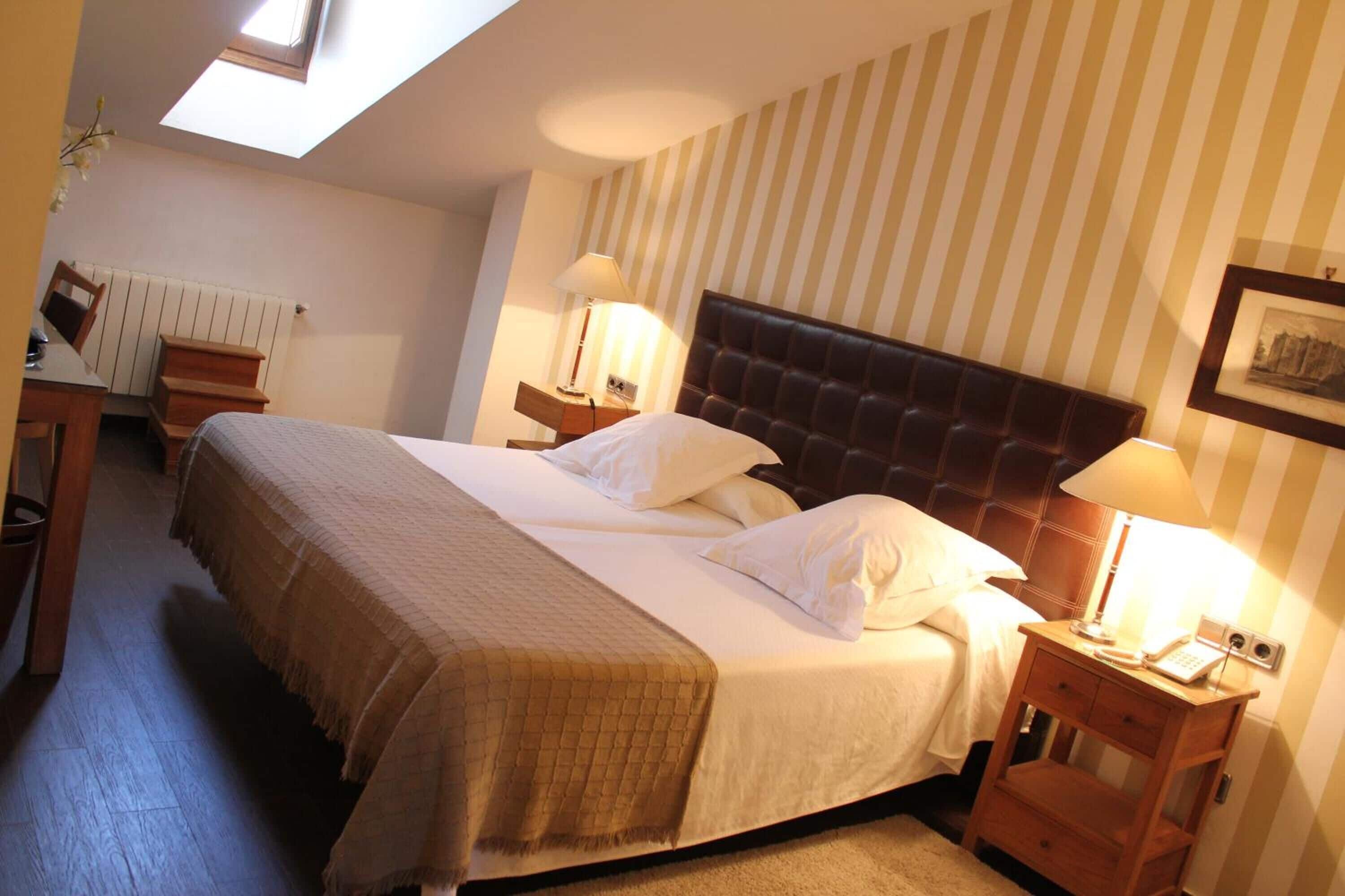 A bedroom with a large bed, two bedside tables, a nightstand, a desk, and a radiator.