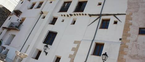 Un edificio de varios pisos con paredes blancas y techo de tejas.