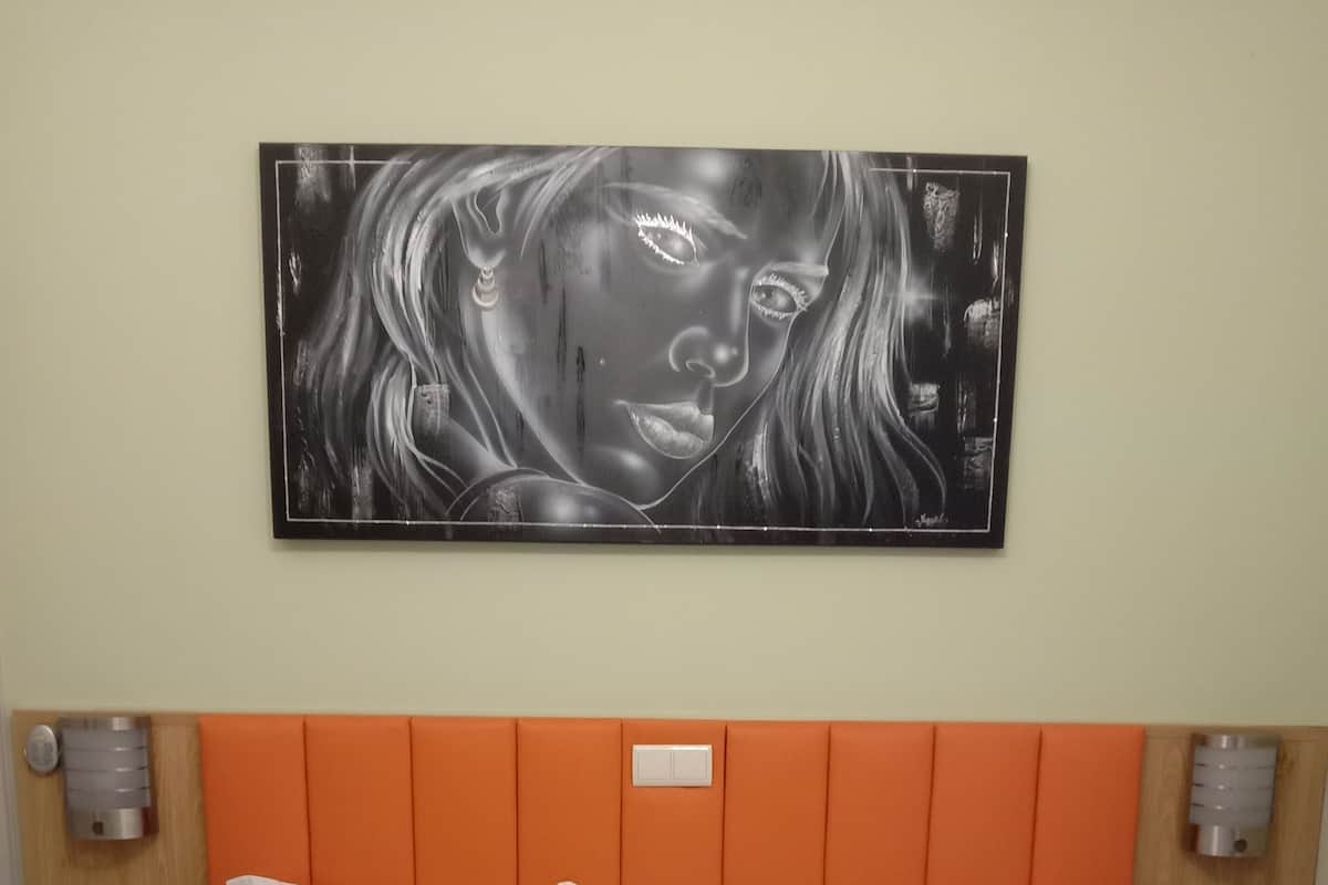 A hotel room with two beds, an orange headboard, and a wall-mounted artwork.