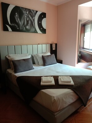 A hotel room with a large bed, a headboard with a circular design, and a wall-mounted artwork. - Residencial Faria Guimarães (Porto)