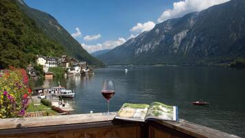 A lakeside view with a wooden deck, a glass of red wine, and a book.