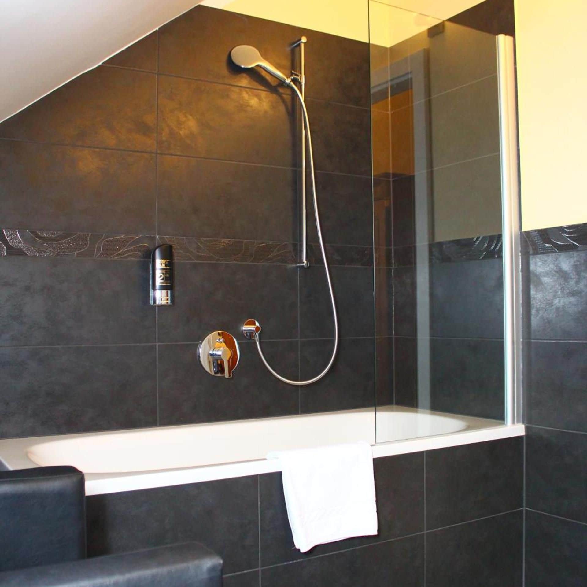 Ein modernes Badezimmer mit einer Duschkabine aus Glas, einer Badewanne und einem Handtuchhalter.