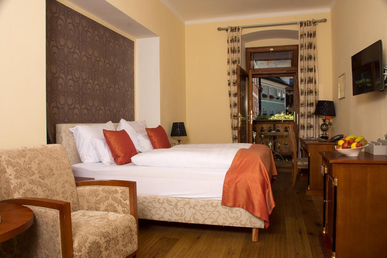 Una habitación de hotel con una cama, una silla, un escritorio, un televisor y una ventana con cortinas.