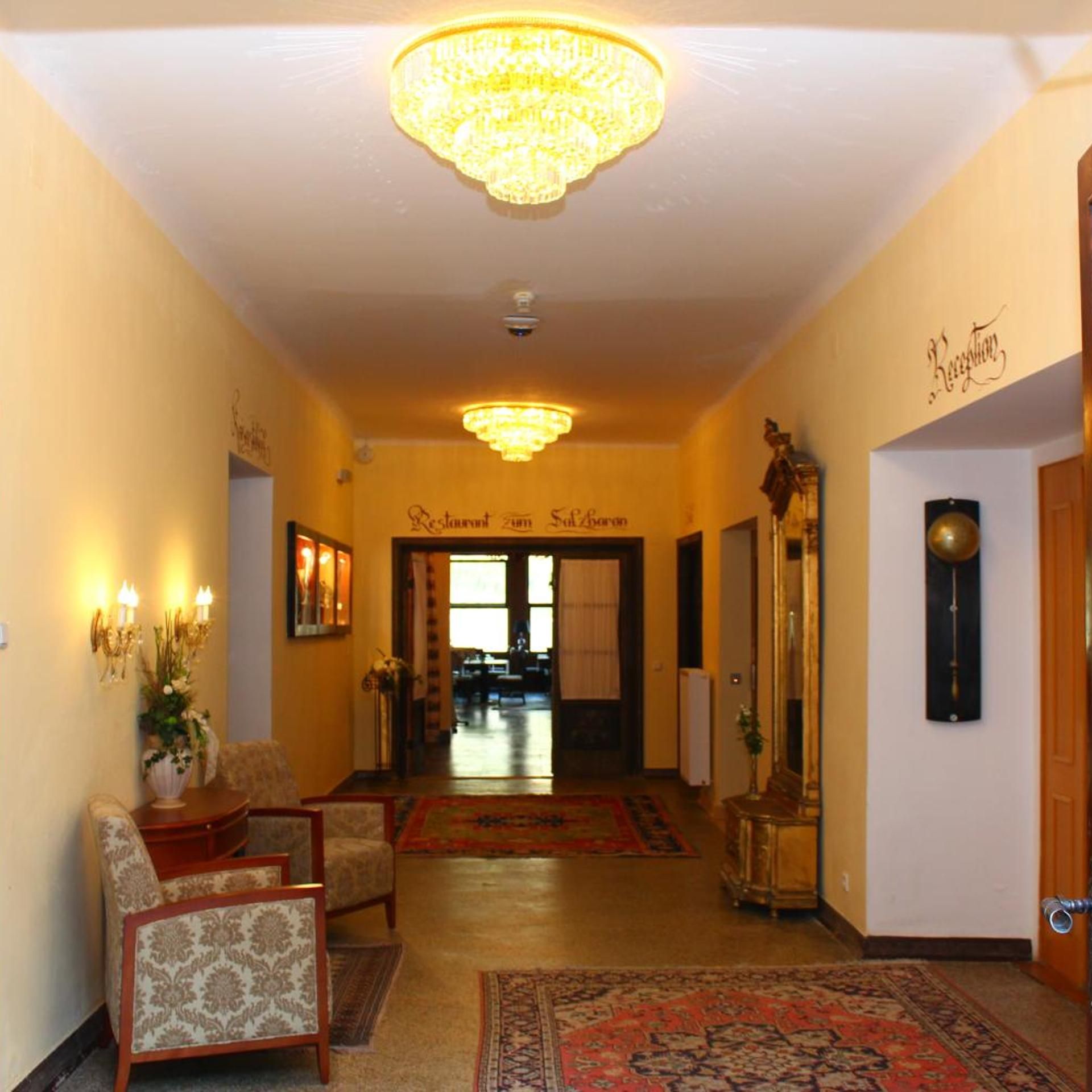 A hotel lobby with a chandelier, a reception desk, and a sign reading 'Restaurant zum Solberg'.