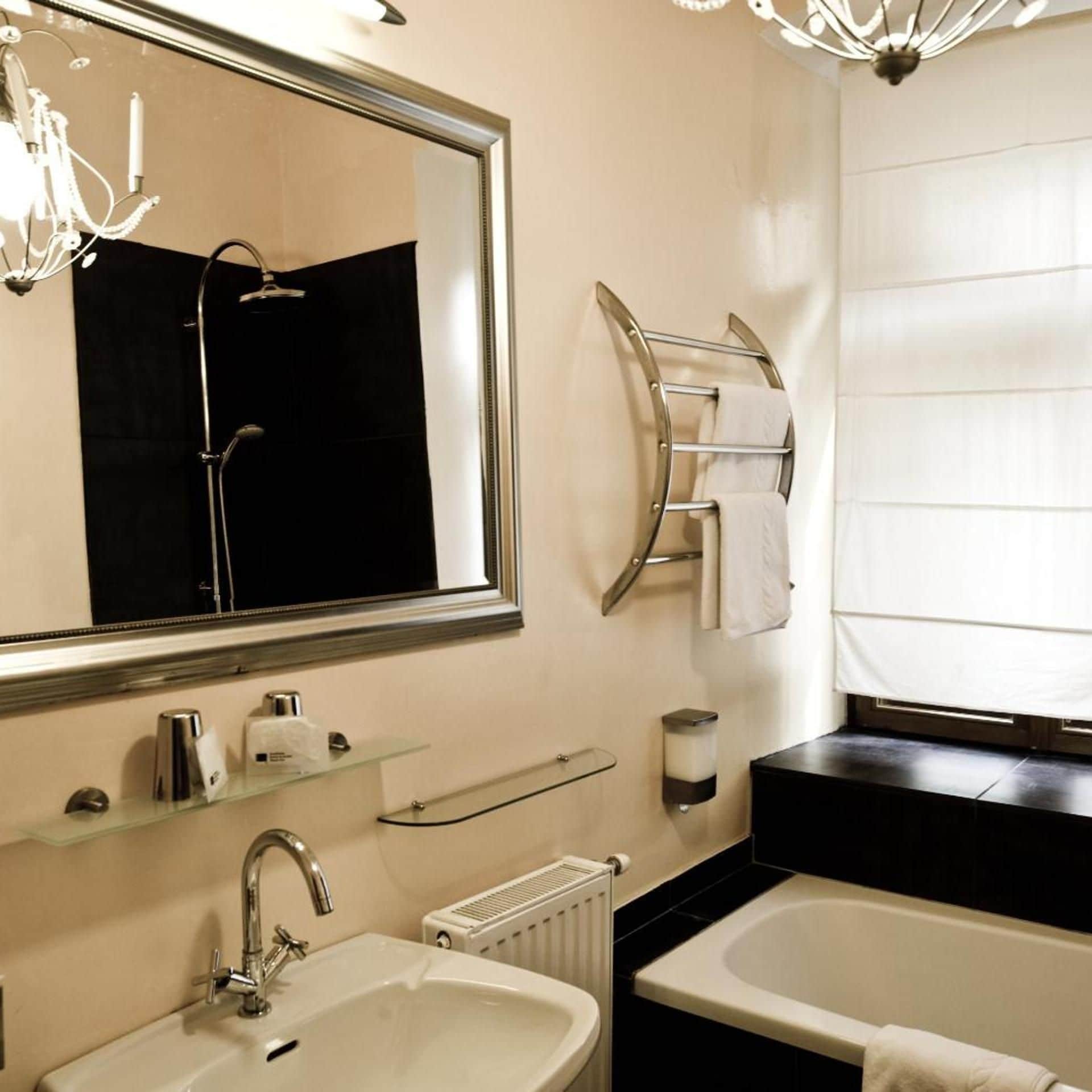 A modern bathroom with a large mirror, a bathtub, a sink, and a towel rack.