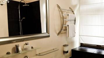 A modern bathroom with a large mirror, a bathtub, a sink, and a towel rack.