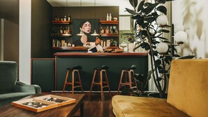 Una zona de bar con taburetes, una barra y un cuadro en la pared.