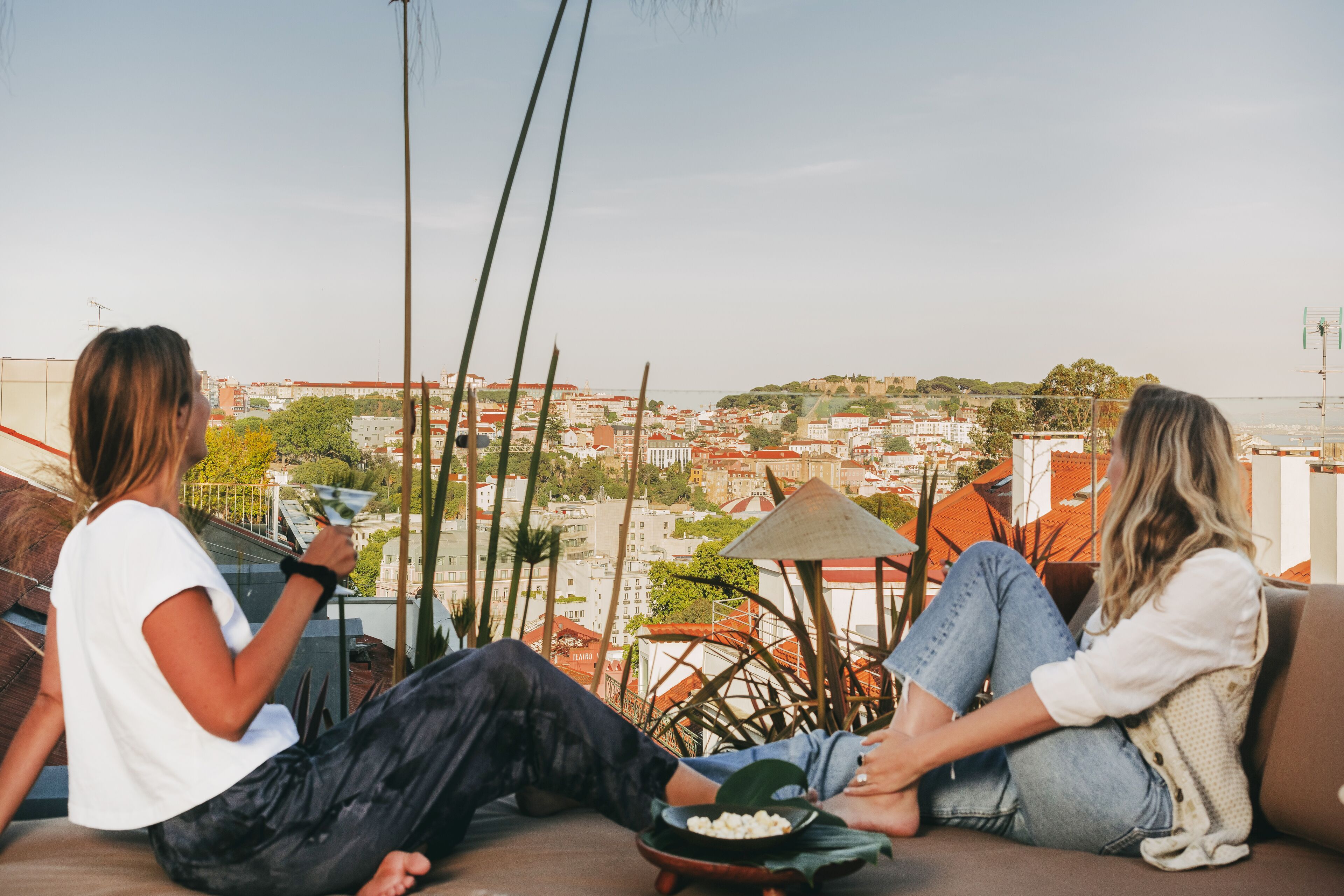 Two people sitting on a sofa with a city view, a table with a bowl of snacks, and a conical roof structure.