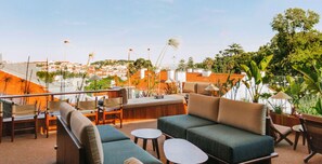 Una terraza en la azotea con mobiliario exterior, incluyendo sofás y sillones, y vistas a la ciudad de fondo.
