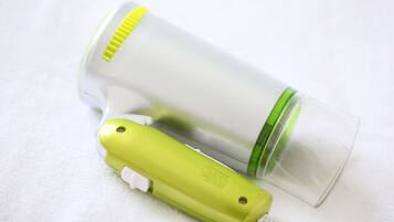 A compact, portable device with a green and white color scheme, likely a personal hygiene item, placed on a white fabric surface.