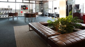 A modern lounge area with a leather sofa, a small dining table with chairs, and a large window providing natural light. - KOKO STAY Sagamihara (Sagamihara)