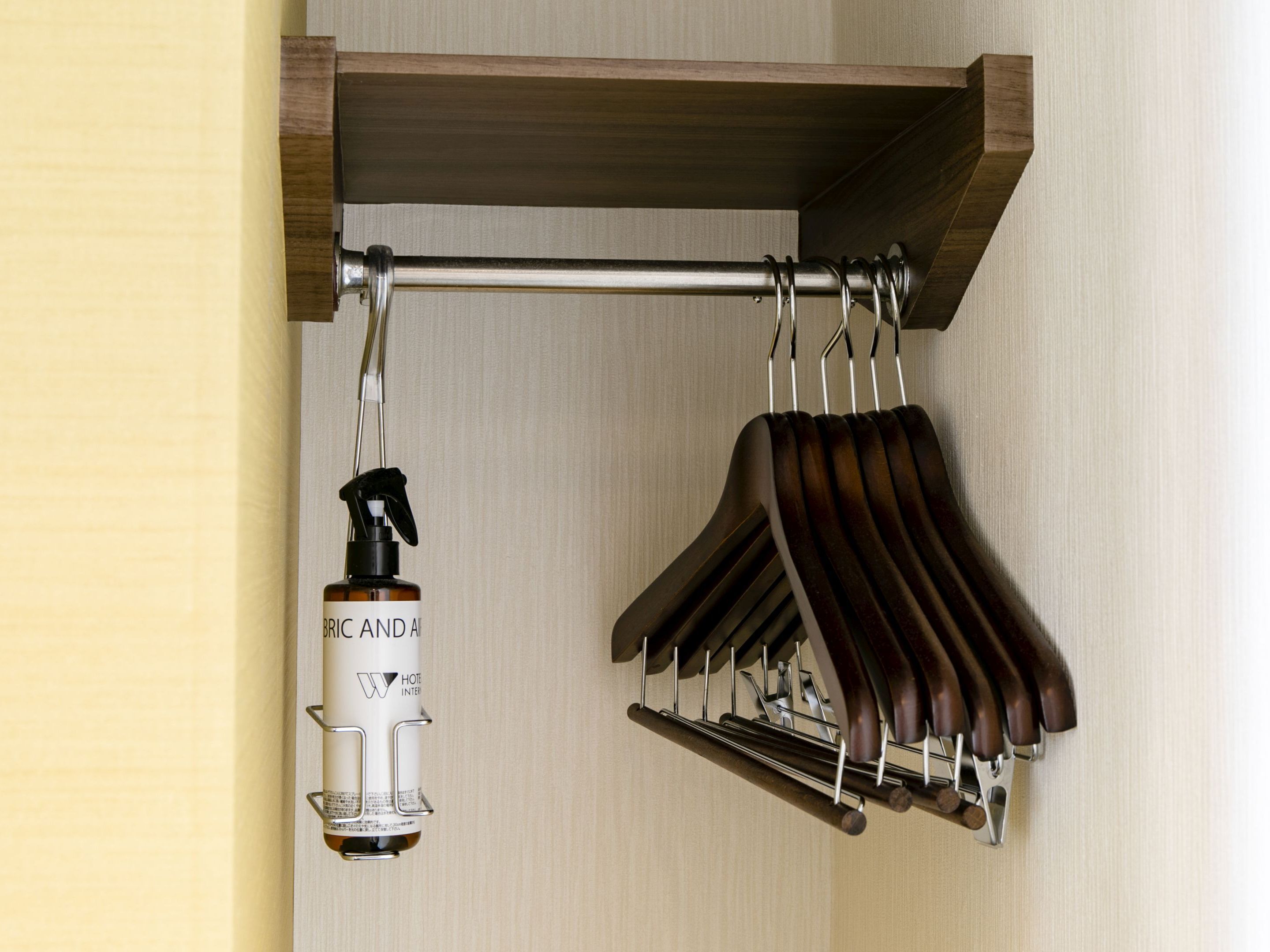 Una estantería de madera con una botella de Bric y el interior del Hotel Air, además de un juego de perchas de madera.