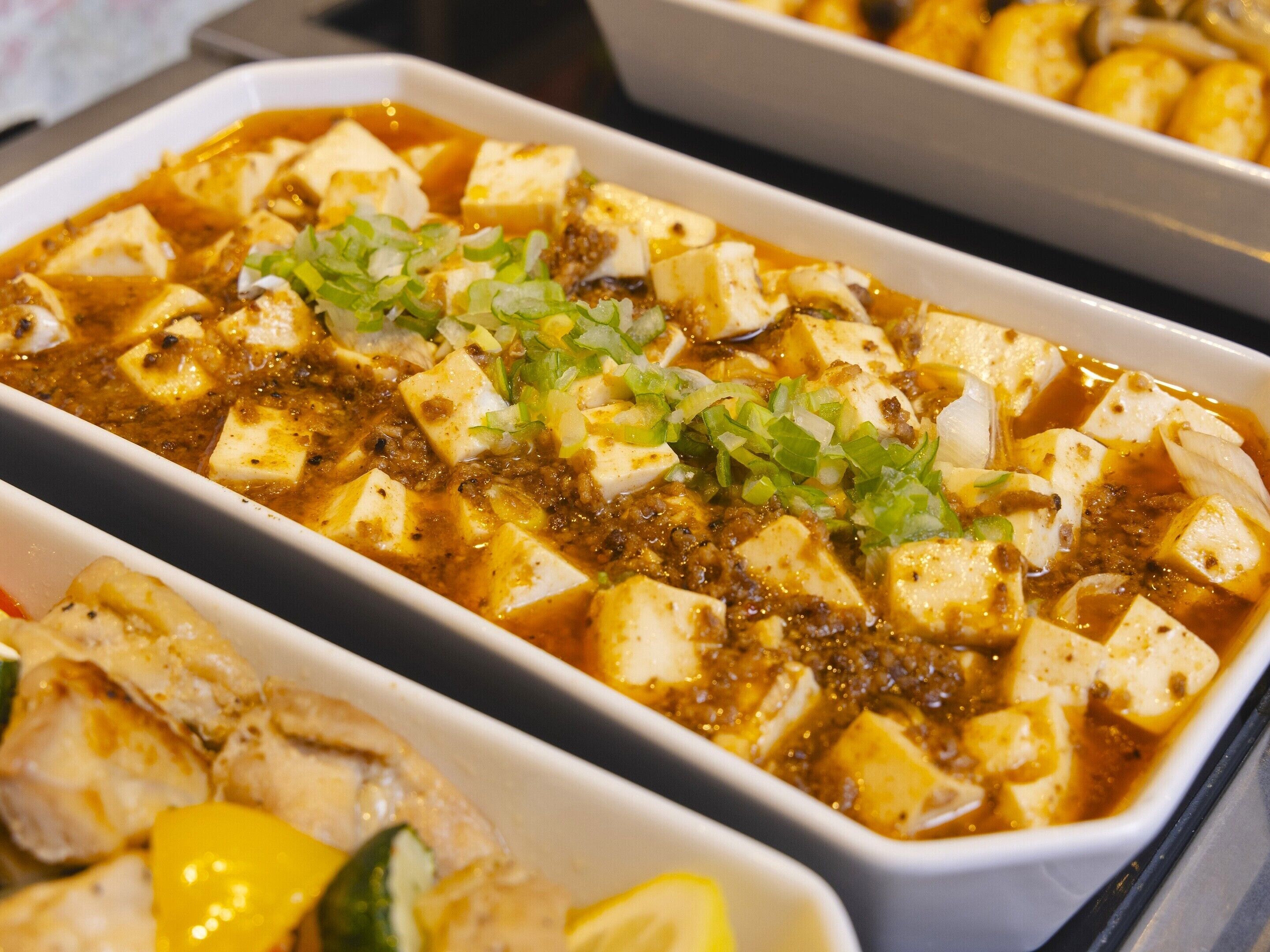 A dish of tofu with green onions and a spicy sauce.