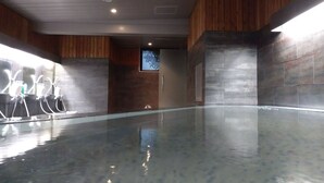 A modern indoor swimming pool with a glass floor, wooden panel walls, and a ceiling with recessed lighting. - KOKO STAY Sagamihara (Sagamihara)