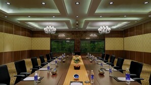 A conference room with a long table, chairs, water bottles, and a floral centerpiece. - Royalton Hyderabad (Hyderabad)
