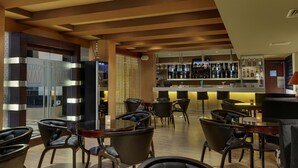 A bar area with multiple seating options, a bar counter with various bottles, and a decorative wall. - Royalton Hyderabad (Hyderabad)