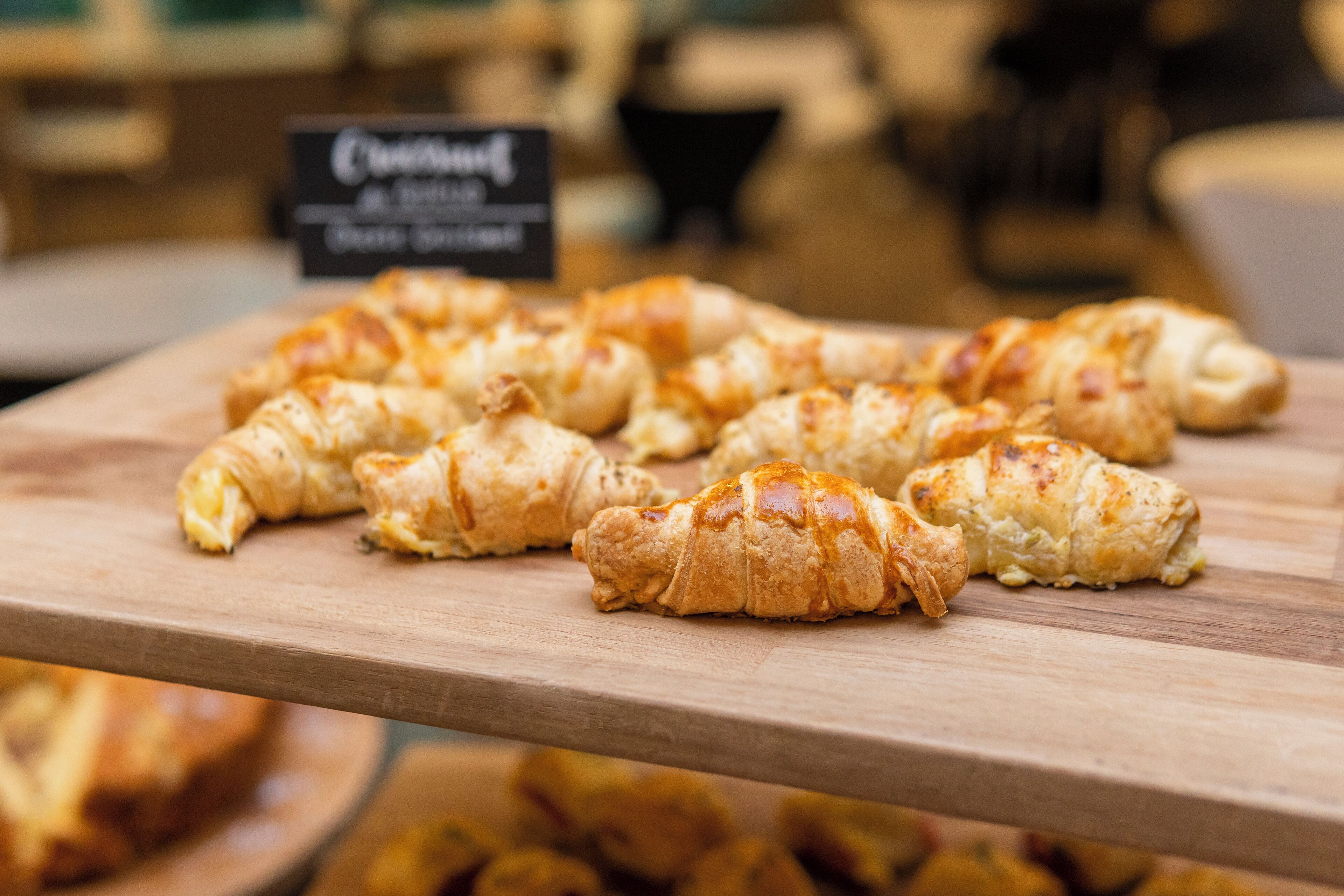 A wooden board displaying several croissants.