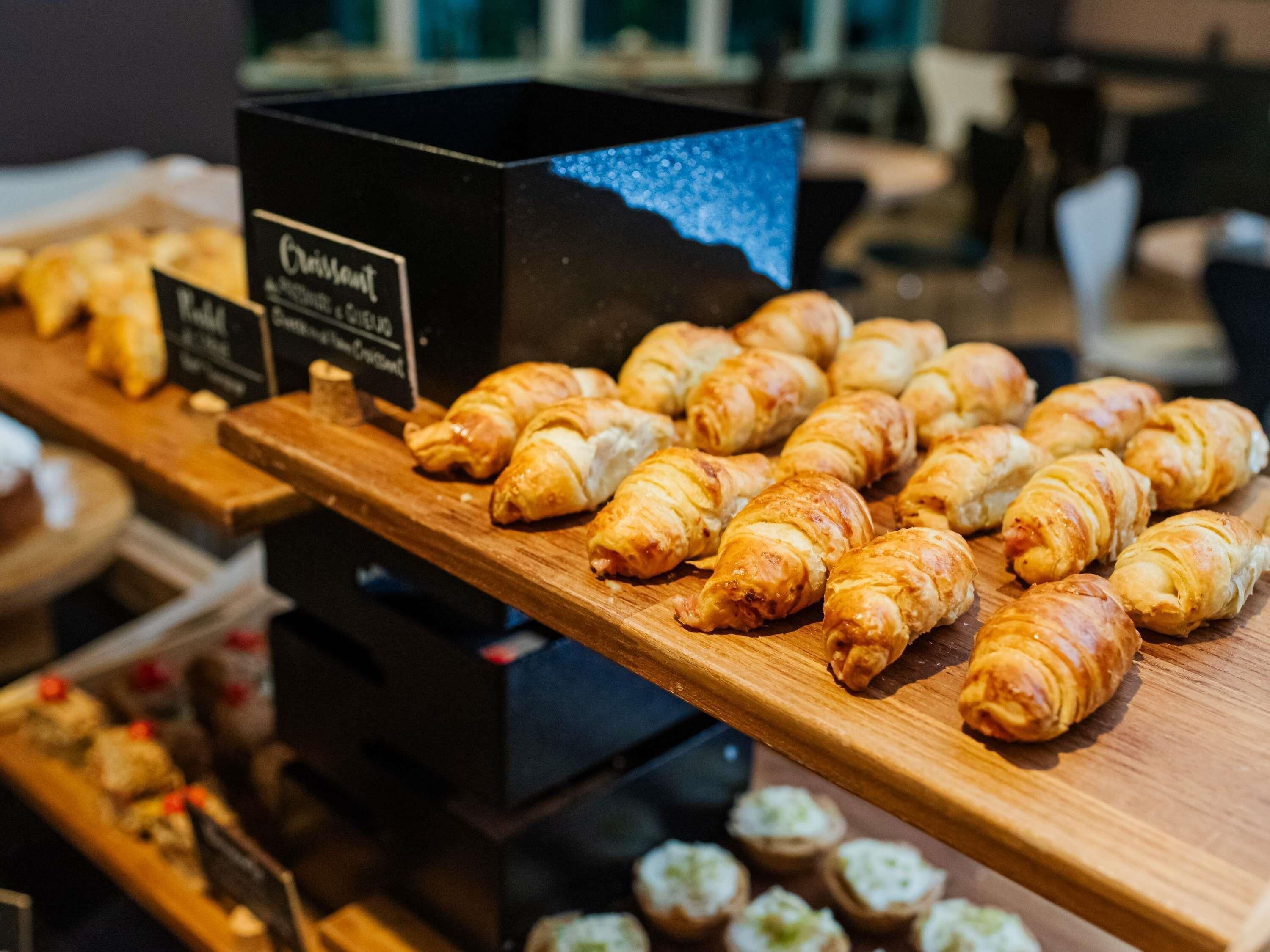 Et bageridisplay med croissanter og et skilt, der viser kaffe og dessertmenu.