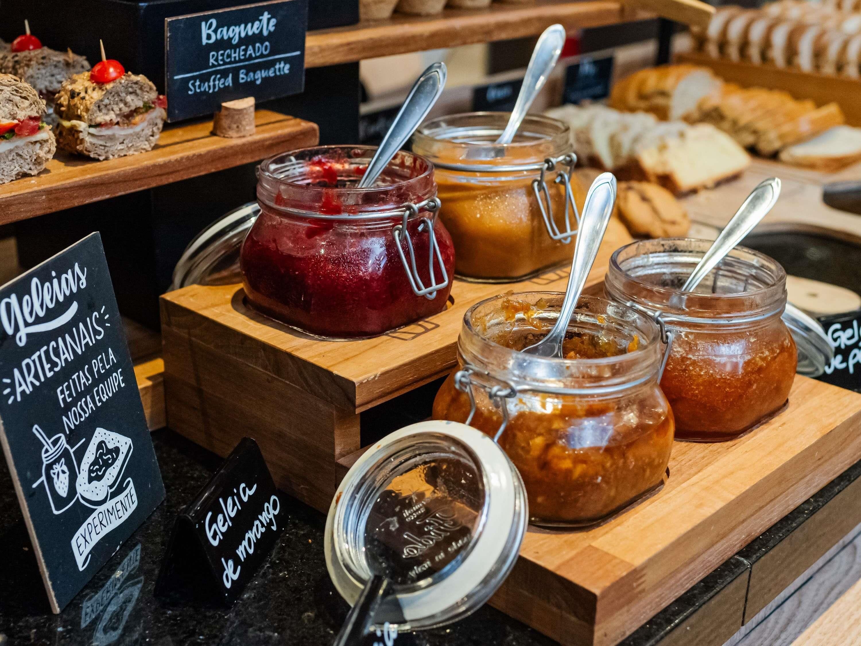 Exposição de alimentos com diversos potes de patês e um aviso indicando produtos artesanais.