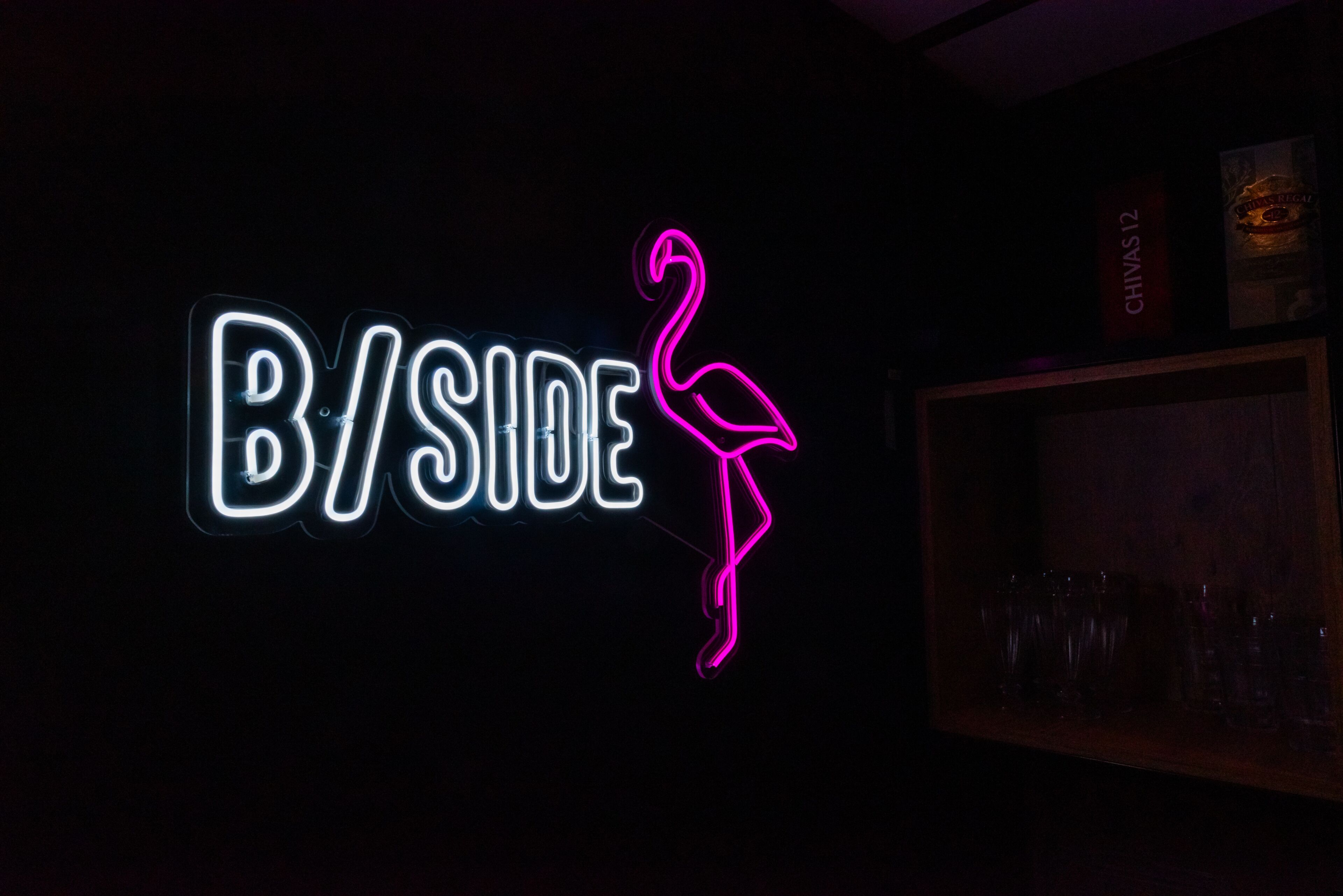 A neon sign with the text "B/SIDE" and a flamingo silhouette.