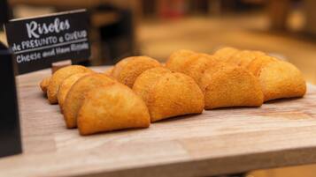 Une variété de viennoiseries dorées et brunes est exposée sur une surface en bois, et une pancarte indique qu’il s’agit de roulés au fromage et au jambon.