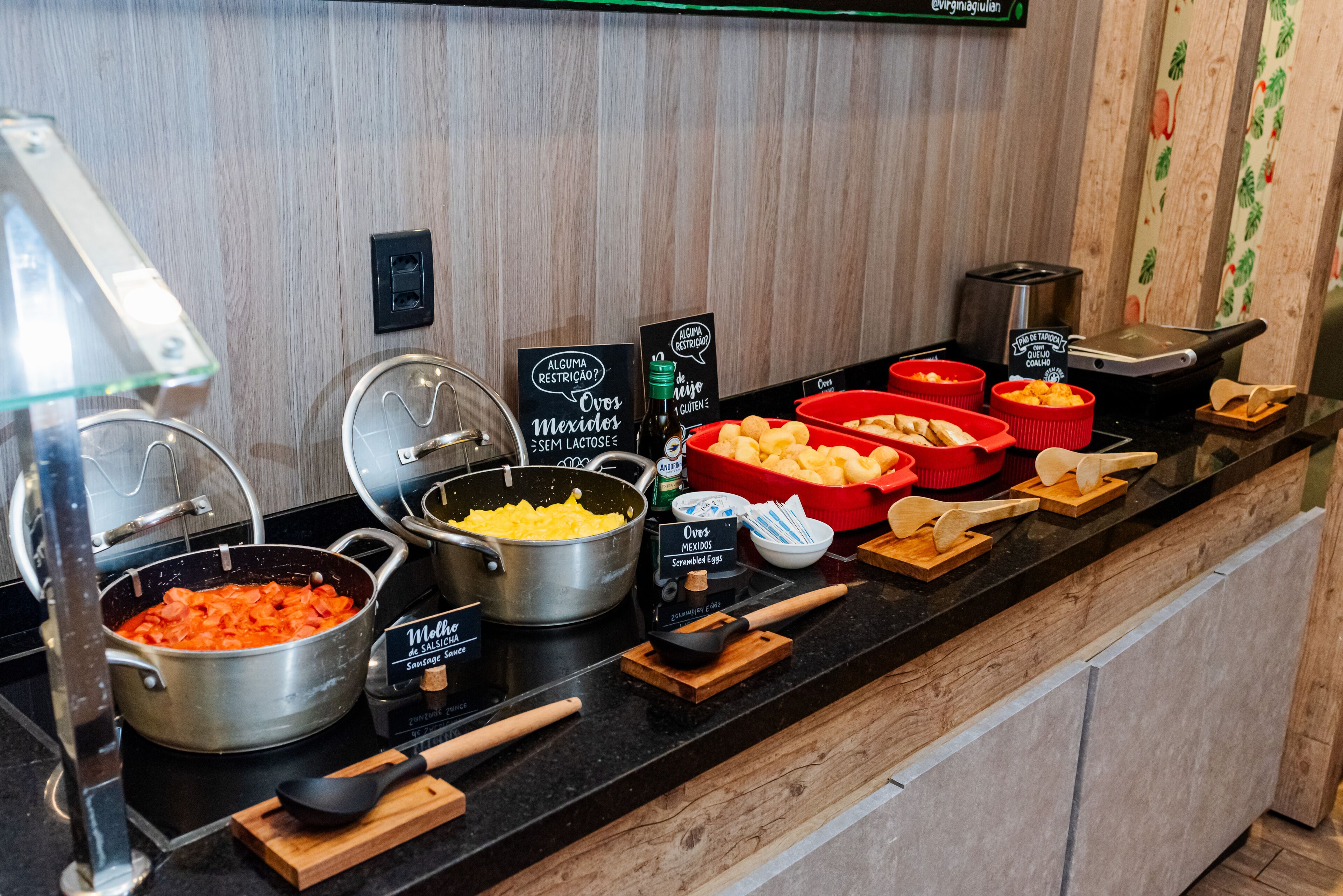 A buffet counter with various food options including scrambled eggs, Mexican dishes, and cheese.
