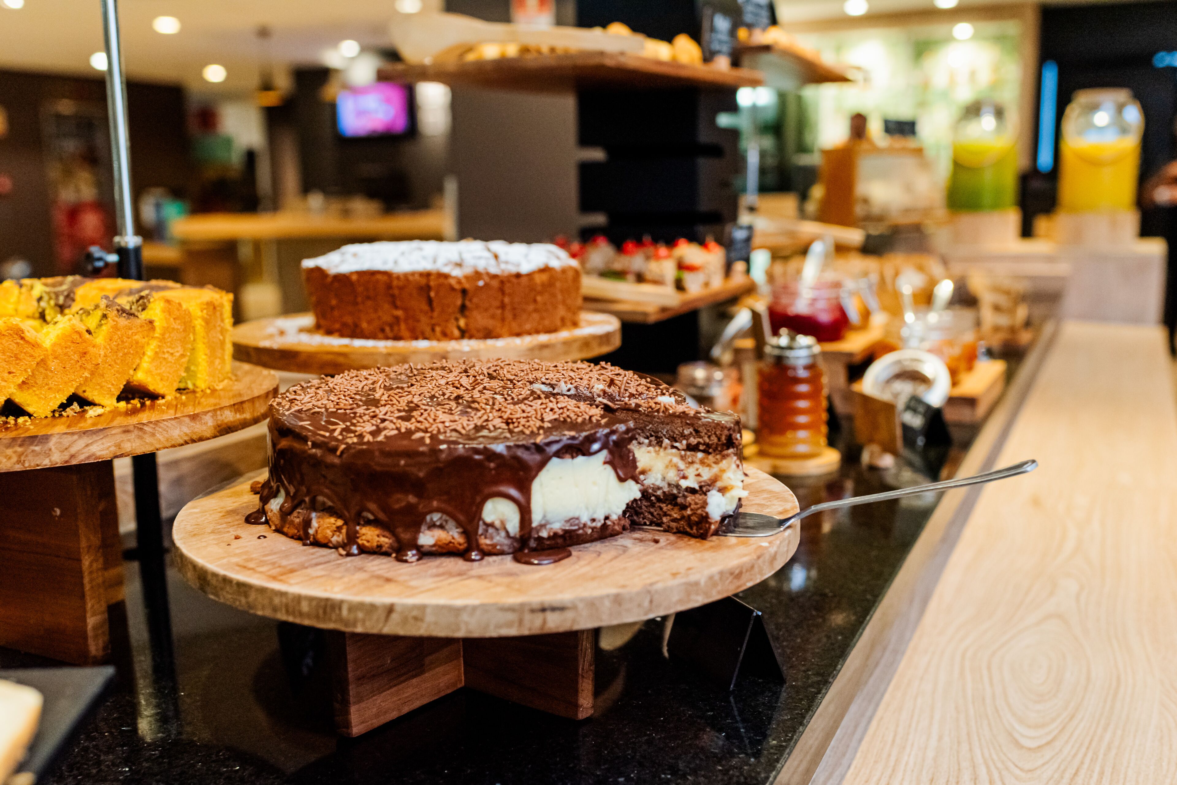 A dessert display with various cakes and pastries on wooden stands.