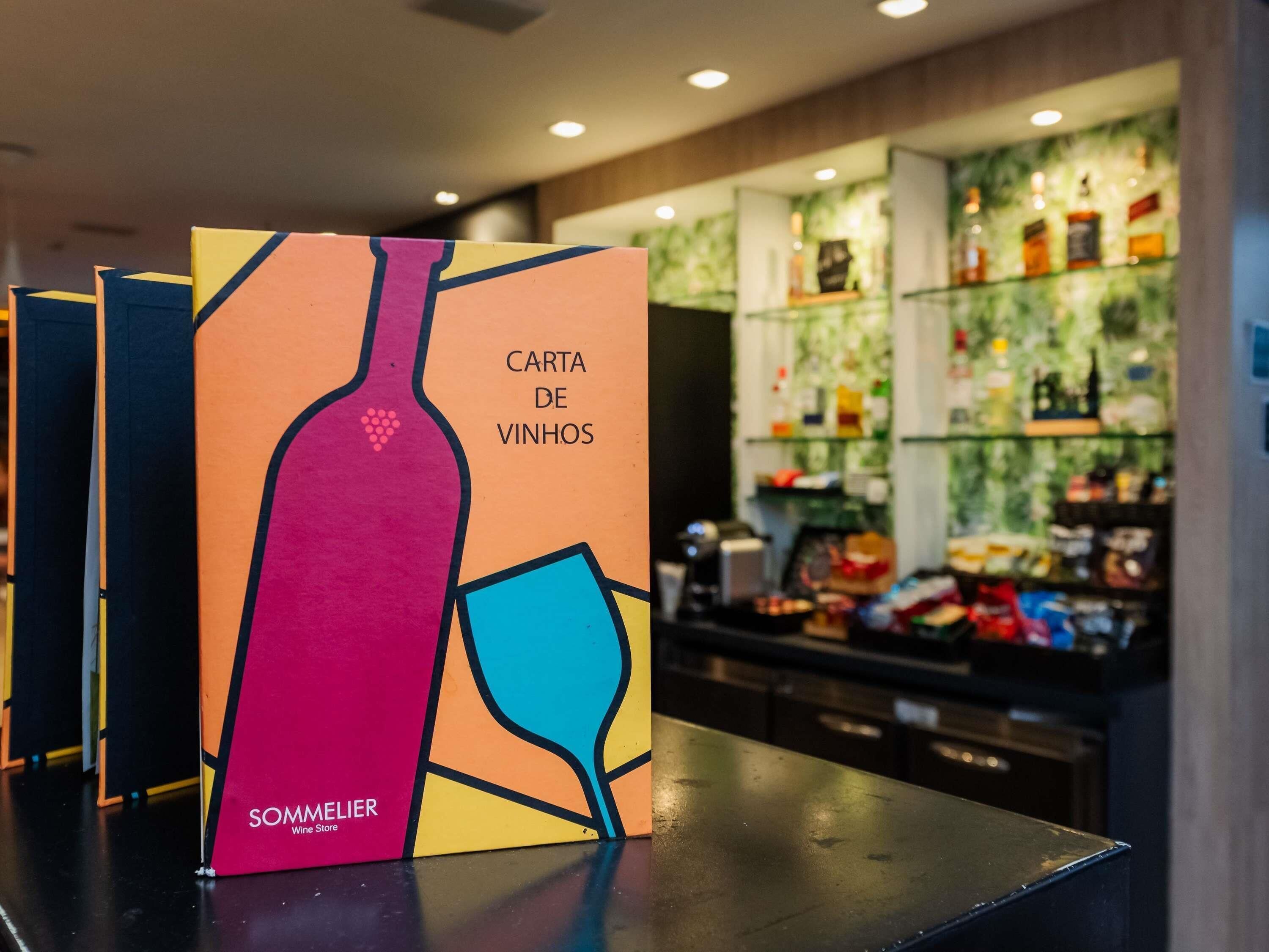 Une boutique de vins avec un présentoir coloré de caisses de vin et un bar en arrière-plan.