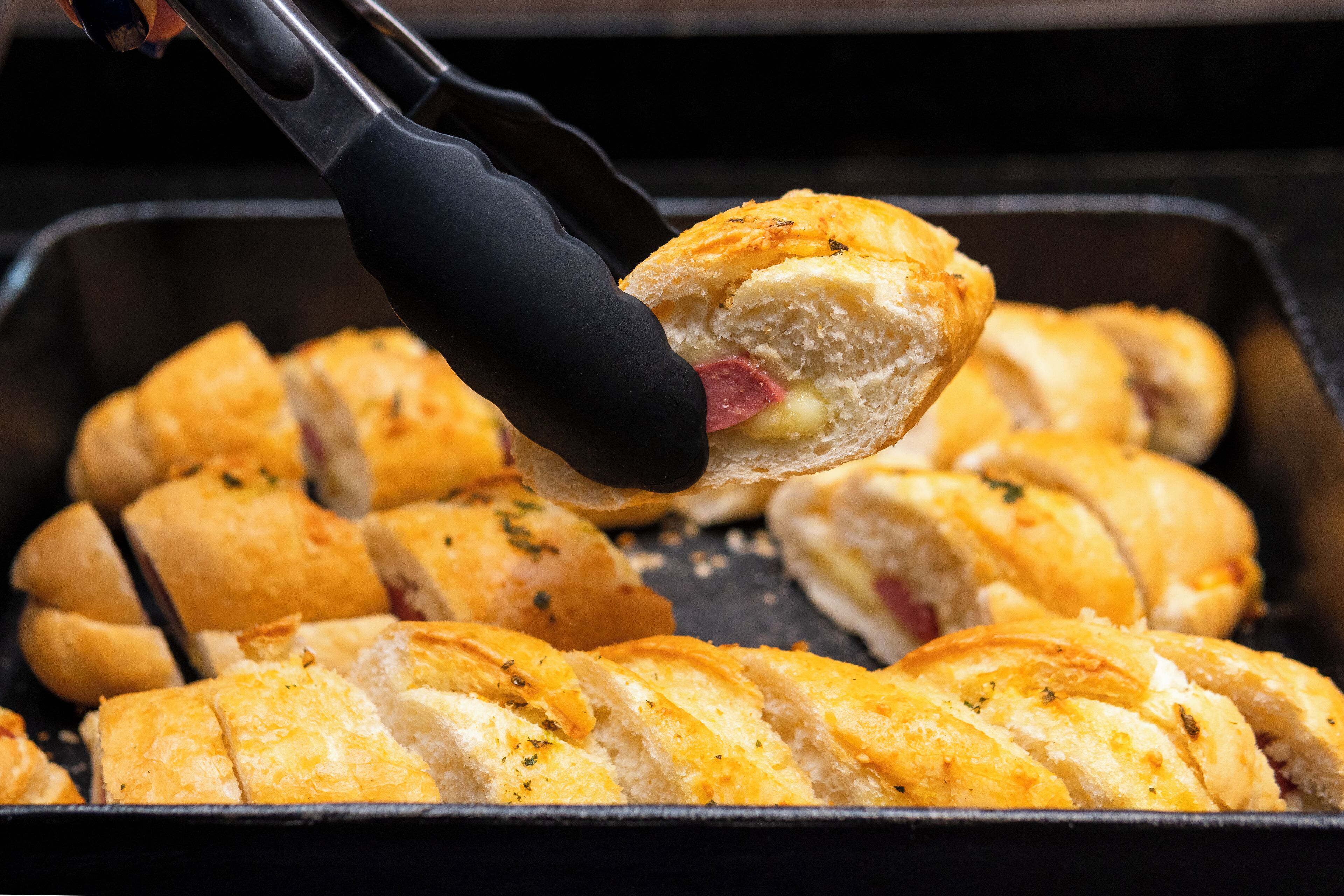 A tray of freshly baked bread rolls with a visible filling.