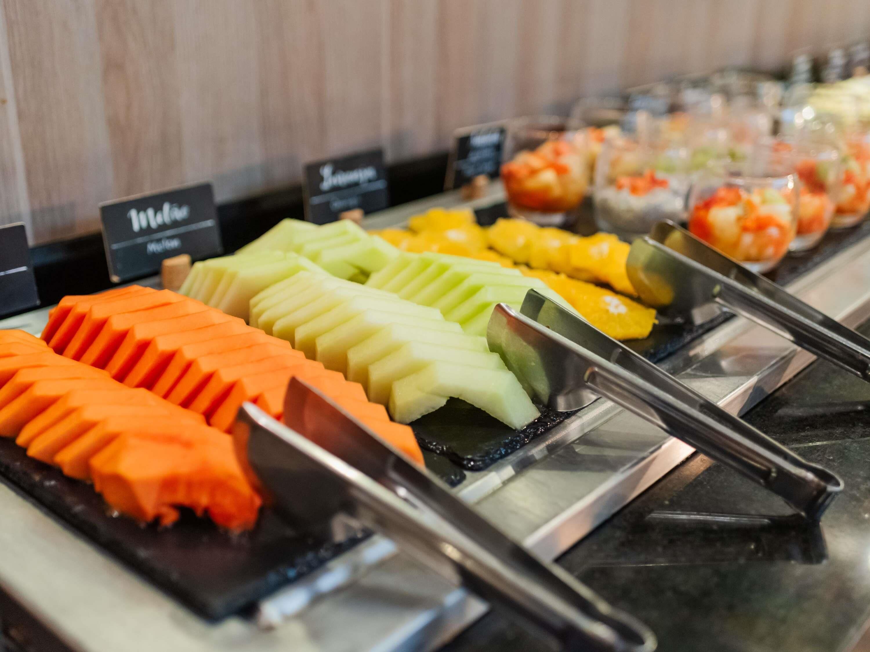 Un bufé con rebanadas de fruta dispuestas con cuidado y un letrero que indica un precio de 11.50.